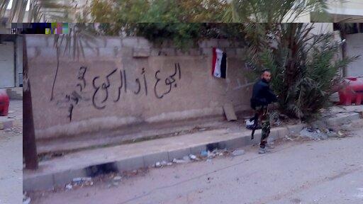 “Kneel or Starve,” written on a wall in Moadamiya by regime soldiers
